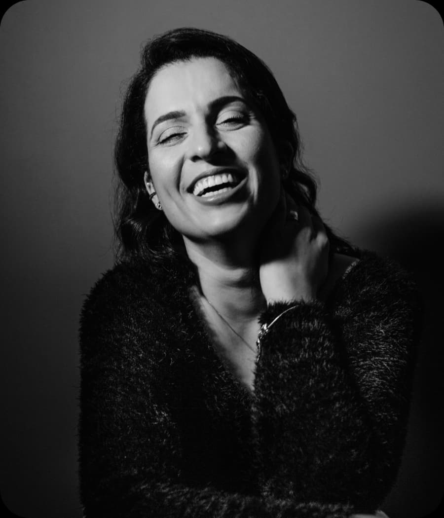 Woman smiling with her head tilted back and hand on her neck.