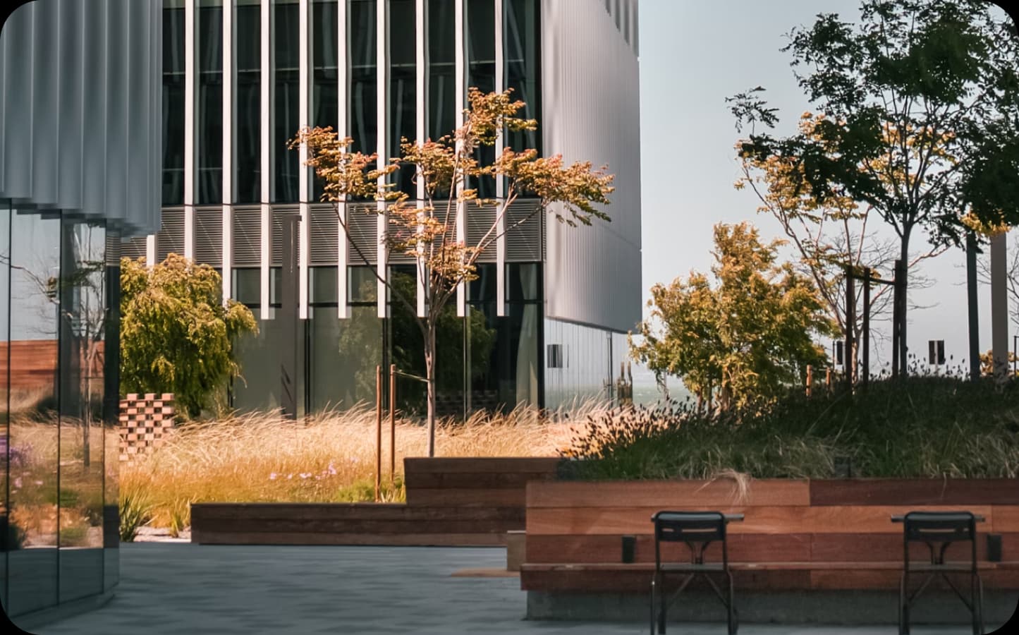 Modern office building exterior with outdoor seating and greenery.
